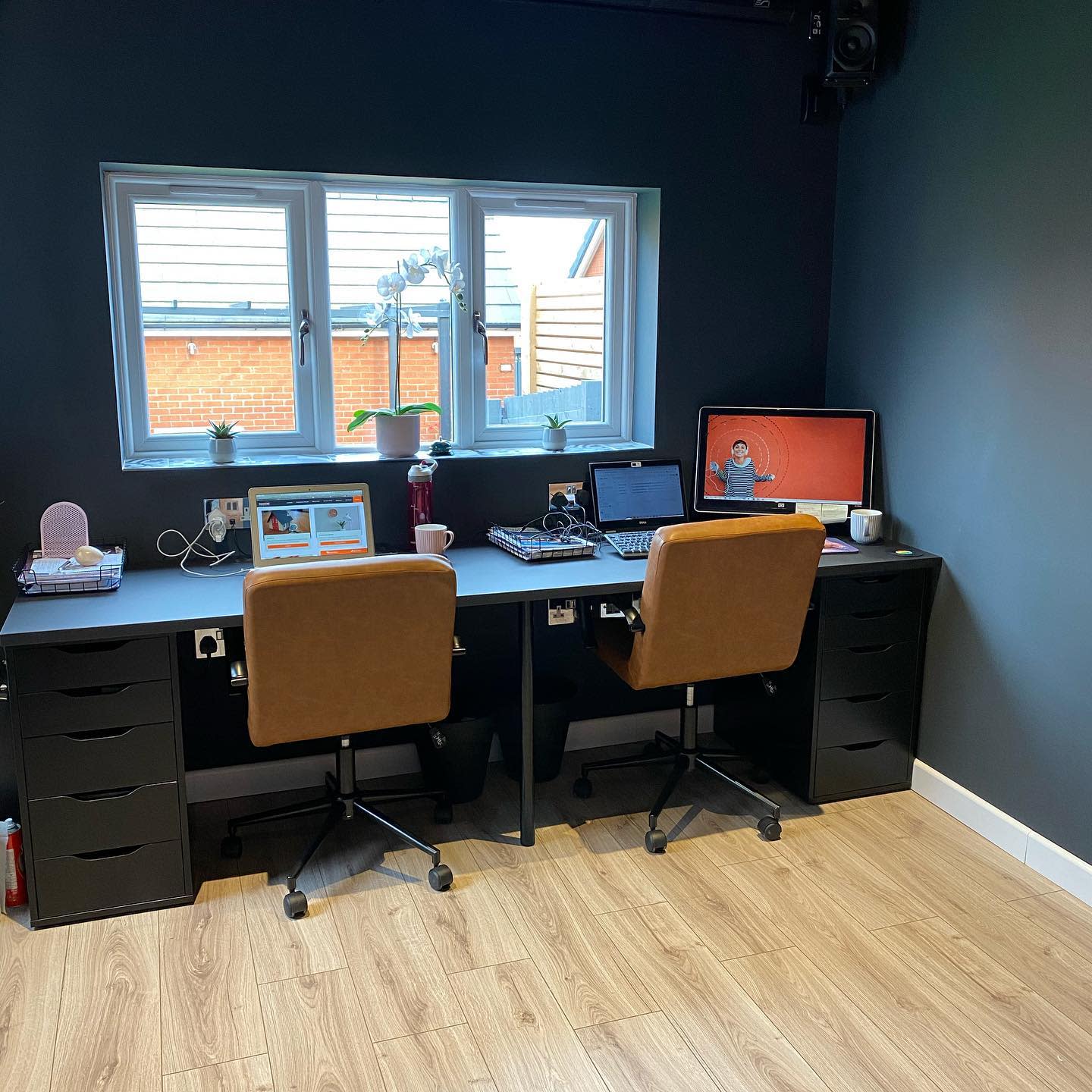 simple dual office setup dark color walls tan chairs 